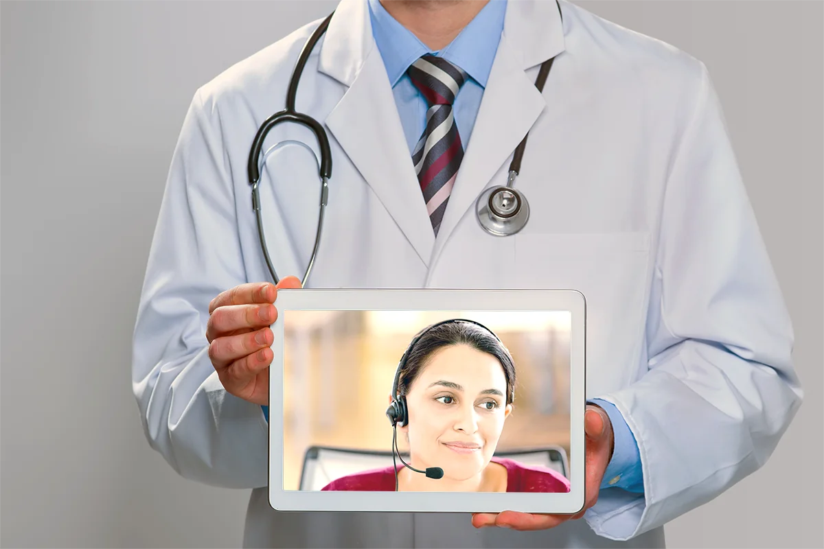 Healthcare provider holding a tablet showing a telehealth interpreter on screen